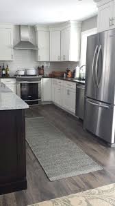 The white is offset with stainless steel countertops and warm, light wood flooring. Floors Reclaime Laminate By Quick Step Flint Oak Planks Laminate Flooring In Kitchen Kitchen Design Home