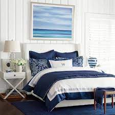 The framed prints, natural headboard, striped bed linens and natural flooring all navy blue and white are classic colors to use when designing a nautical themed bedroom. Nautical Chic In Navy Coastal Style Coastal Style Bedroom Coastal Bedroom Coastal Bedrooms