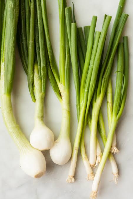 Spring onions (left) have a distinct round bulb, while scallions/green onions (right) remain straight and slender., AI generated