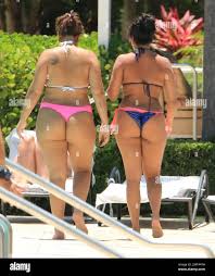 A curvier Natalie Nunn gets cheeky with a pal poolside as she balanced a  cup of water on her her friend's ample bottom. The Bad Girls star is  filming for a new