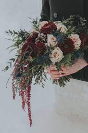 Although a burgundy and gold wedding color scheme is often used to convey a regal mood for a wedding, these paper circle garlands show that you can have a little fun with it. A Winter Bridal Bouquet For A Wedding At Emerald Lake Lodge With Hanging Burgundy Amaranthus Winter Bridal Bouquets Gold Wedding Bouquets Blue Wedding Bouquet