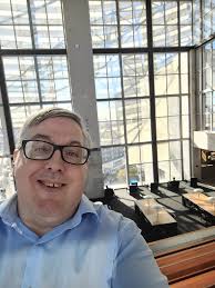 Charles E. McCloud, of Julian. He stands in an open shed holding a hammer  over an anvil. Notes