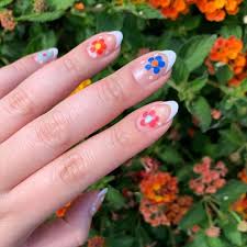 Hands with short manicured nails colored with dark purple nail polish holding a flower. 31 Flower Nail Art Designs Pretty Floral Manicures For 2021 Glamour