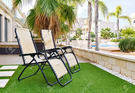 Aqua sling high end pool furniture chaise lounge neck pillow. Two Empty Lounge Chairs On Artificial Lawn Grass Inside Of Personal Area Backyard Residential Summer Villa View To Modern Homes With Swimming Pool Luxury Summer Holidays Lifestyle Concept Stock Photo Picture And
