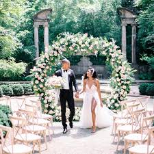 Outdoor green secret garden with arched entry and gate and a fountain in the middle and red brick and black iron gate. 51 Stunning Wedding Arch And Arbor Ideas