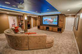 The cozy room incorporates a large sectional couch and a tv area, updated overhead lighting and new floors, which were lowered during the renovation to provide the homeowners with more headroom. Basement Remodeling Finishing Contractor Lafayette Indiana