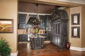 A dark gothic kitchen with heavy black cabinets, a burgundy hood over the cooker and lots of potted greenery and lights. Gothic Black Kitchen Exotic Moldings Custom Wooden Cabinets And Furniture