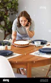 Young housewife bending over table and enjoying smell of freshly baked cake  during lunch at home Stock Photo - Alamy