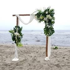 You can observe bunches of flowers placed here and there on this arch and we're sure you can use tropical flowers in your wedding for your wedding bouquet. An Elegant Arch By The Moody Ocean Maunalanibayhawaii Professional Pictures Coming Soon Chels Tropical Wedding Theme Wedding Archway Wedding Beach Ceremony