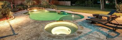 Stamped concrete patio with cedar pergola surrounded by synthetic grass and water features call elite pools and landscaping in dallas tx and surrounding cities. Richardson Pool Builder Richardson Pool Service Company