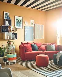 A Brightly Colored Living Room With Ochre Walls Is Burnished With A Red Sofa And Ottomans Soggiorno Ikea Divani Da Soggiorno Idee Arredamento Soggiorno