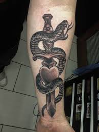 Dagger tattoo designs signify strong emotions of courage, bravery, and hardship. Black Ink Snake With Dagger Tattoo On Left Forearm