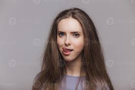 Shot of beautiful brunette female licks lips with tongue, has pure healthy  skin, dressed casually, isolated over grey background. Lovely woman shows  tongue, poses indoor. Facial expressions. 11565528 Stock Photo at Vecteezy