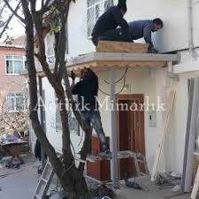 Binanın dış cephesiyle uyumlu olarak yapılan bir kapı üstü sundurma seçimi tüm binanın estetik karakterini yükseltiyor. Kapi Onu Cati Cati Kati Dekorasyonu