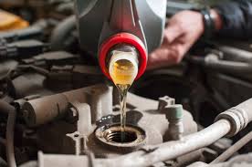 Golden engine oil is being poured from a container into a car engine, highlighting how regular maintenance can prevent issues where a car can overheat due to lack of oil.