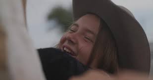 A kid wearing a hat playing with a horse