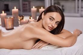 Schöne nackte frau, die im spa-salon liegt und mit vielen kerzen zur seite  schaut | Premium-Foto
