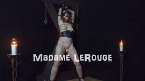 顺从的红发熟女被绑在十字架上，用衣夹折磨