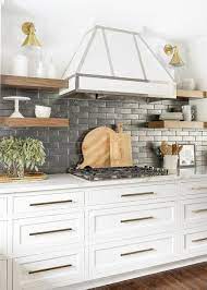 The contrast between the black and white in the kitchen will create a dramatic look but will still let the white keep the space bright and inviting. White Kitchen With Black Backsplash Tiles Transitional Kitchen