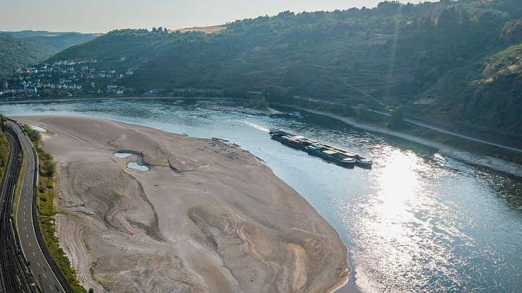A dried-up riverbed of the Rhine in Germany, showing cracked earth and exposed historical debris during the historic 2022 drought.