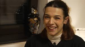 D'Mäna wëll op d'Eurovisioun. Sangen ass awer net der Studentin hir eenzeg  Passioun. Mir léieren d'Kënschtlerin privat kennen. De Reportage haut den  Owend em 19:00 am Magazin op der Tëlee an duerno