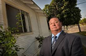 Louie Martinez III stands in front of the window, where he lived as a  10-year-old boy, was looking through when he witnessed a police officer  being shot. Photo by Steven Georges/Behind the