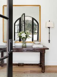 A round rope and metal mirror hangs over a styled turquoise blue spindle console table. Dark Stained Console Table With Spindle Legs Transitional Entrance Foyer