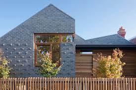 Contrast is provided with the dark gray garage door and front door. This House Is Built Around Four Courtyards