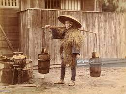 A Japanese Labourer Wearing A Straw Hat And Straw Raincoat And Carrying Water Buckets Circa 1890 Japanese Hat Hats Straw Hat