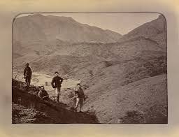 Photograph of the Khan of Lalpura, the leader of the Lalpura region of Afghanistan, and his followers on a mountainside. The Khan is standing in the middle of a group of Afghan