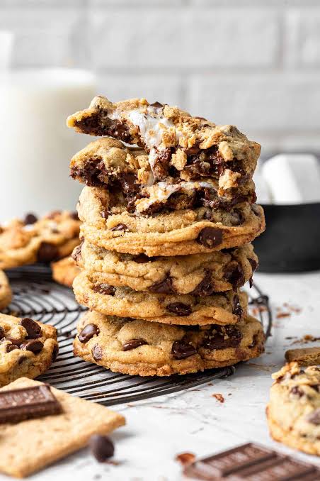 S'mores Chocolate Chip Cookies stacked on a plate with gooey marshmallow tops