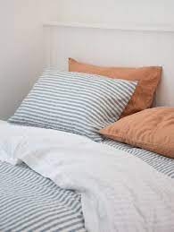 This large bedroom is divided into different spaces including the main bed with its fluffy silk sheets and headboard, the day bed and its simple brown color, and a bay window to the far end with a patterned window. Our Contemporary Marine Blue Stripe French Linen Bedding Styled With Out Sandalwood Pillowcases Shop The Striped Bed Sheets Bed Linen Design Bed Linens Luxury