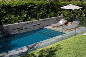 Swimming Pool With Framing Wall From Dark Stone With Varying Textures And A Glas Safety Fence Contempor Landscape Design Services Garden Pool Landscape Design