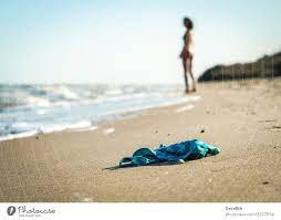 Niedriger Blickwinkel eines jungen Mannes, der mit nackten Füßen am Strand  steht - ein lizenzfreies Stock Foto von Photocase