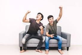 Two Friends Sitting On Sofa And Enjoying Play Video Game Together At Home Friend Pictures Poses Friend Pictures Playing Video Games