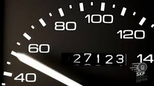 A person inspecting a used car engine, representing the importance of checking factors beyond just how many miles should be on a used car.