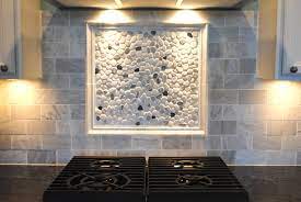 It features marble stones that appear like smooth pebbles, and it can be used as a marble pebble backsplash, wall tile, or countertop in residential and commercial projects as well as flooring in homes. White Washed Tiles Backsplash With A Frame Containing White And Black River Rock Decorations Four Sets Rock Backsplash River Rock Backsplash Marble Backsplash