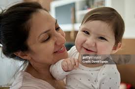 Happy Mother Holding Her Smiling Baby At Home High-Res Stock Photo