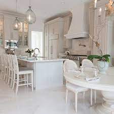 All white kitchen with white moldings and cabinetry, wood top island, wide plank wood flooring, brass hardware. Gray French Kitchen Design French Kitchen