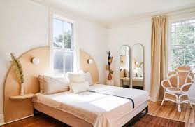 The headboard with nightstands are afixed to the wall, hanging from a rail mounting. The Headboard Sconce Might Be Our Favorite Hotel Inspired Small Bedroom Hack Emily Henderson