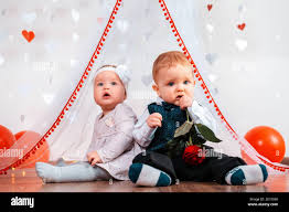 Valentine S Day Baby Boy And Baby Girl Posing Together The Boy Chews A Rose Sadly In The Background Is A Decorated White Background Stock Photo Alamy