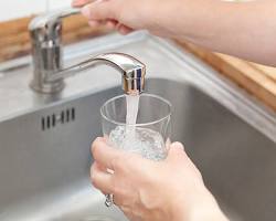 Image of someone enjoying a glass of NYC tap water with the city skyline in the background