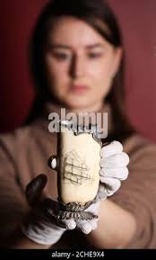 EDITORIAL USE ONLY Curator Danielle Thom unveils a piece of decorated  scrimshaw, a whale's tooth, which will go