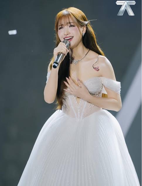 Hòa Minzy thường lựa chọn váy midi tông trắng hoặc kem, kết hợp kiểu tóc nhẹ nhàng để tạo vẻ ngoài trong trẻo và thanh lịch.
