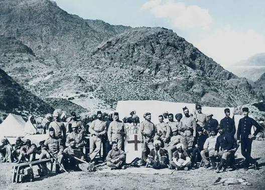 Photograph of the Khan of Lalpura, the leader of the Lalpura region of Afghanistan, and his followers on a mountainside. The Khan is standing in the middle of a group of Afghan
