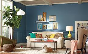 Beige and blue living room features blue paint on upper walls and wainscoting on lower walls alongside a backless beige settee adorned with blue and yellow pillows facing a wood and iron coffee table atop a jute rug. Blue Living Room Ideas The Home Depot