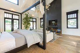 A black and white bedroom with a black wall behind the bed, and white quilt, matched up with white drawer cabinets. Modern Black And White Master Bedroom With Neutral Rug And Wood Floors Hgtv