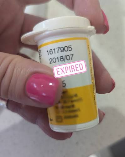 A hand checking the expiry date printed on a medicine bottle label