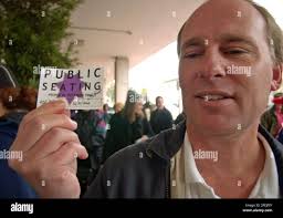 Stephen Hazel smiles as he holds up his winning lottery card for one of 27  daily public seats available to sit in