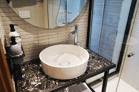 A chic boho bathroom with mosaics on the wall, potted greenery, a wooden caddy and candles. Hobo Nectar Pulse